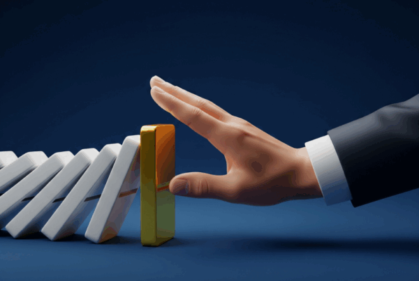 Main d'un expert stoppant la chute d'un domino doré, symbolisant la prévention et la gestion proactive du précontentieux AT/MP.